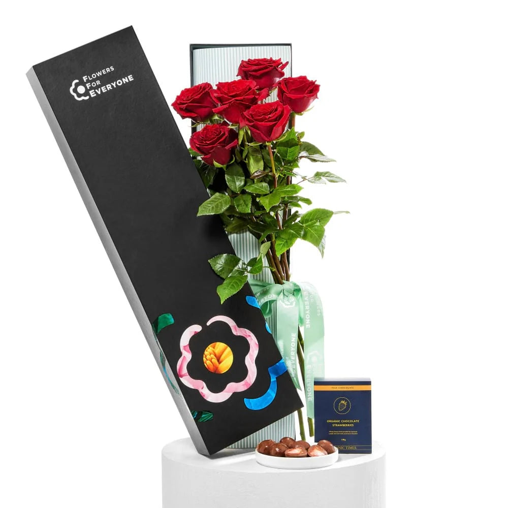 12 Red Roses with Strawberries arranged in a black gift box with lush greenery and a ribbon for romantic anniversary flowers and same day delivery flowers