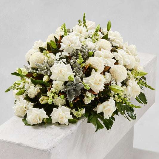 TRADITIONAL WHITE MIXED CASKET with white roses chrysanthemums and lush greenery for funeral flowers sympathy flowers and same day delivery