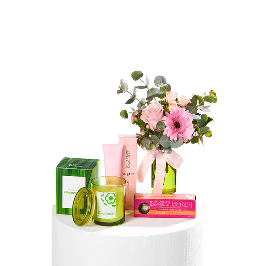 Rosy Delight Hamper with pink flowers in a vase alongside hand cream candle tea and rocky road treat for birthday gifting and same day delivery